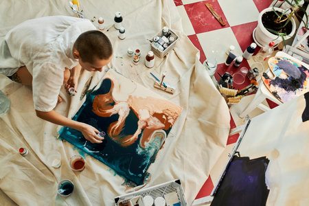 Horizontal from above view shot of professional artist creating fluid art picture adding some acrylic paintの写真素材