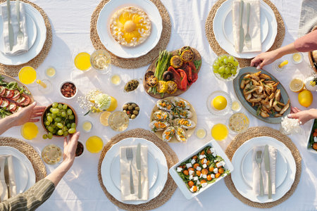 Overhead view of multiethnic group of young adult and middle aged hands reaching for assorted...