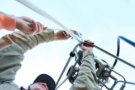Middle aged man and woman adjusting metal frame of hot air balloon burner system outdoors, hands...