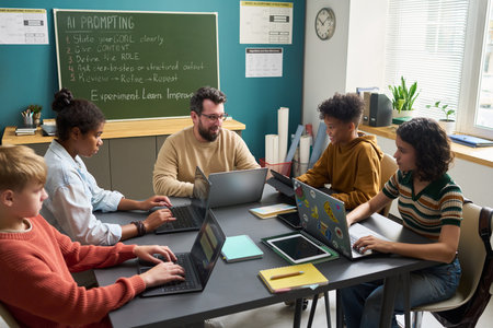 Group of diverse teenagers collaborating with Caucasian man using laptops in classroom, engaging in...