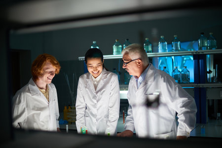Smiling male and female medical students with their experienced mentor working on their project in...