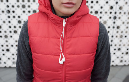 Female runner outdoors. Crop shot of unrecognizable woman wearing vest and earphones standing...