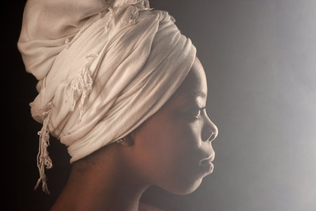 Profile portrait of attractive African American woman wearing white turban looking into the distance...