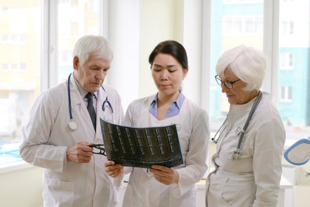 Group of experienced male and female radiologists looking at X-ray of patient after MRI procedure...