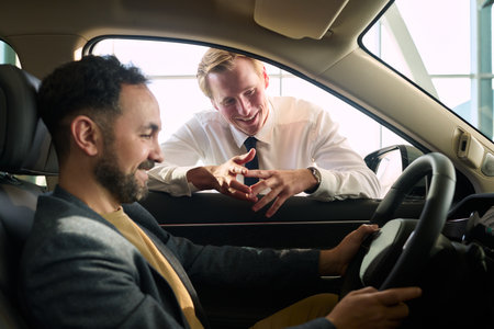 Young adult man sitting in driver seat holding steering wheel while smiling young adult male...