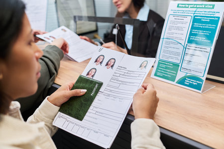 Young adult woman holding passport and visa application form with attached ID photos, interacting...