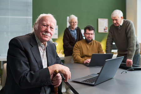 Senior Caucasian man sitting at table holding cane while senior Caucasian woman, senior Caucasian...