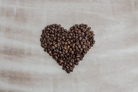 Heart from coffee beans on wooden background