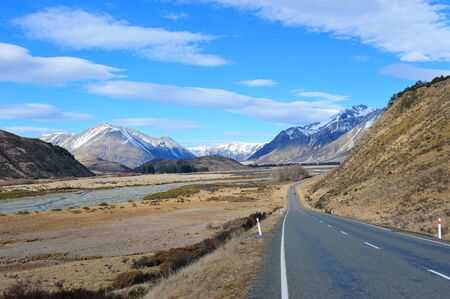 Scenic road with snow mountains in the background in New Zealand