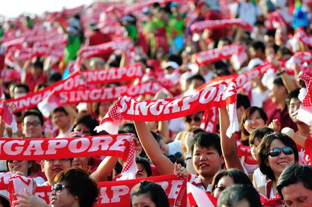 Enthusiastic audience waving the red Singapore scarves during National Day Parade 2012 on August 09, 2012 in Singaporeのeditorial素材