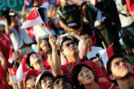 Audience waving Singapore flags during National Day Parade 2012 on August 09, 2012 in Singaporeのeditorial素材