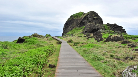Wooden board walk leading to volcanic rock formation at San Xian Tai in Taiwanの写真素材