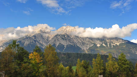 Clouds floating above snow capped mountains in Austriaの写真素材