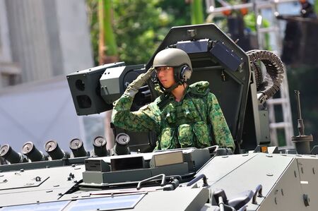 SINGAPORE - AUGUST 09: Soldier in a Terrex infantry carrier vehicle saluting to the President during Singapore National Day Parade 2010 at the Padang August 09, 2010 in Singaporeのeditorial素材
