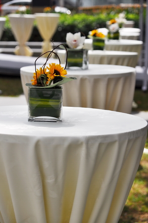 Row of reception tables covered with white cloths and decorated with flowersの写真素材