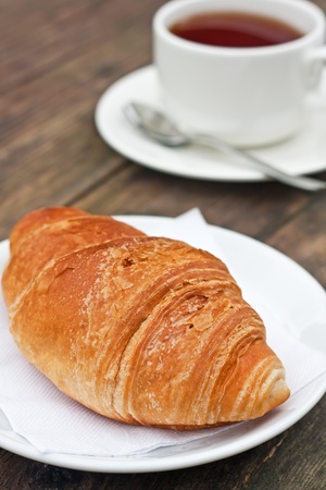 Fresh-baked croissant and cup of tea on wooden table
の写真素材