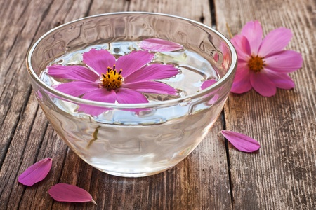 bowl of water and floating flower sitting on wooden tableの写真素材