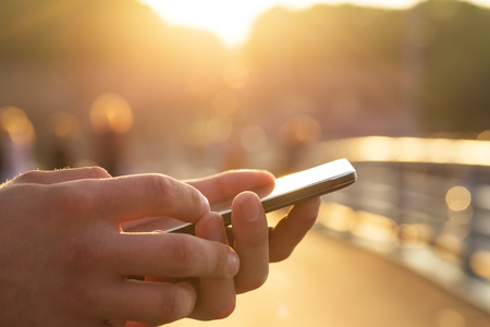 Man using his Mobile Phone outdoor, close up