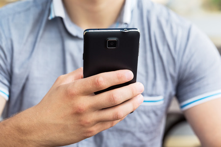 Man using his Mobile Phone outdoor, close upの写真素材