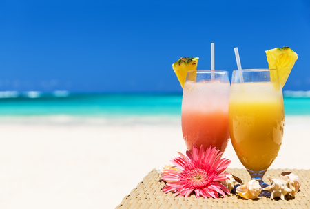 Two tropical fresh juices on white sandy beachの写真素材