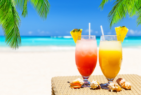 Two tropical fresh juices on white sandy beach in Punta Cana, Dominican Republicの写真素材