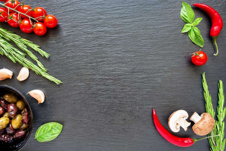 Food ingredients on dark background. Tomatoes, spices, garlic, mushrooms and basil leaves on black...
