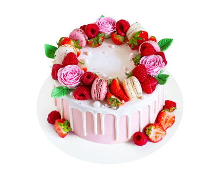 Birthday sweet cake with berries, macaron and floral decor isolated on a white background. Beautiful pink cake decorated with macarons, raspberries, strawberries and sugar rose flowers.の写真素材