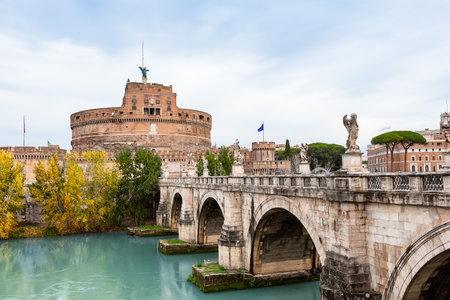 Castel Sant'Angelo and the Sant'Angelo bridge over Tiber river against cloudy sky in Rome, Italy....