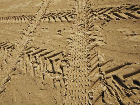 Geometric intersections of tire tracks on the wet sand of the beach
