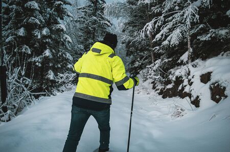 Man walking hiking in a snow, Scandinavian winter. Walking with a sticks, in a pro gear, with a high...
