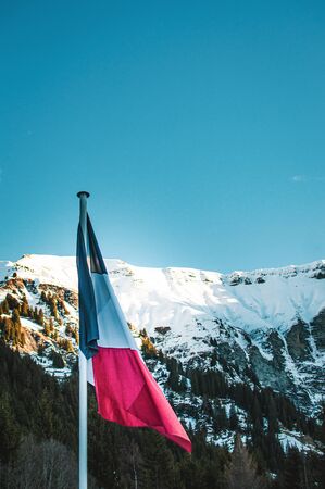 picture of a french flag flapping in a wind. Mountains behind the flag, snow on m ountains, French alps.の写真素材