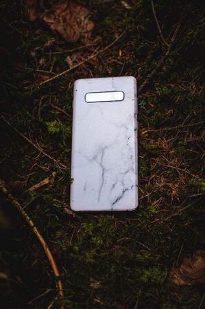 mobile phone on a moss in the forest. Dark picture, moodie feeling and colours. Brand new mobile...