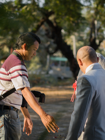 MANDALAY, MYANMAR - JANUARY 01, 2013: WEDDING PHOTOGRAPHER TEACHING BRIDE AND GROOM HOW TO POSEのeditorial素材