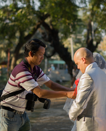 MANDALAY, MYANMAR - JANUARY 01, 2013: WEDDING PHOTOGRAPHER TIDYING GROOM'S SUITのeditorial素材