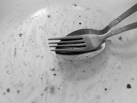 BLACK AND WHITE PHOTO OF FINISHED PLATE WITH FORK AND SPOON