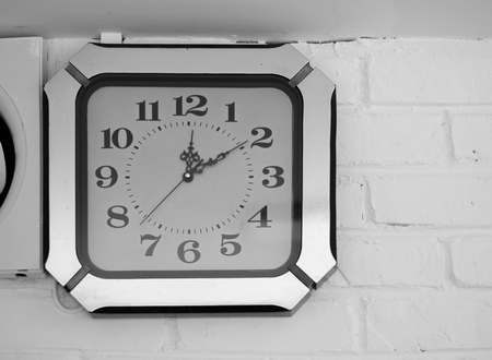 BLACK AND WHITE PHOTO OF ANTIQUE CLOCK MOUNTED ON WALLの写真素材