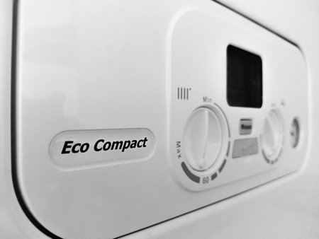 Close?up of a modern boiler control panel with temperature knobs, digital display, and reset button. Clean, minimal design suitable for home energy, heating, and efficiency themes.
