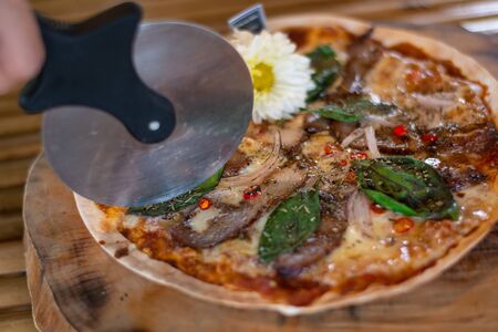 Pizza is a savory dish of Italian origin, consisting of a usually round, flattened base of leavened wheat-based dough topped with tomatoes, cheese, and often various other ingredients baked at a high temperature, traditionally in a wood-fired oven.の写真素材