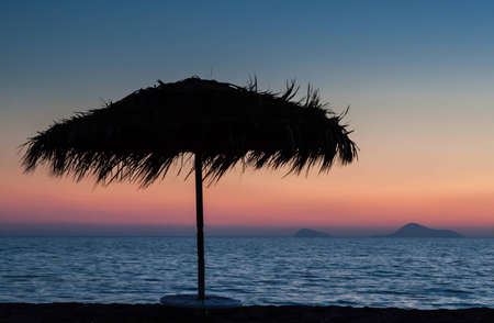 Sunset on the beach with parasolの写真素材