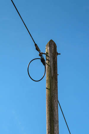 a telephone line runs on a wooden pole under blue skyの写真素材