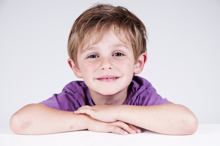cute boy smiling in a studio hanging on a tableの写真素材