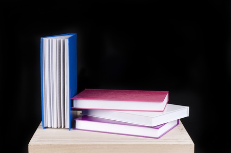 four colorful books on a wooden table on a black backgroundの写真素材