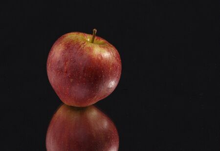 apple on black background with mirror reflectionの写真素材