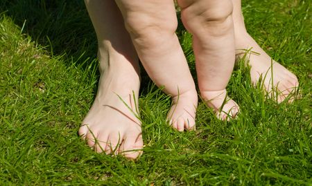 feet of baby and adult on the grassの写真素材
