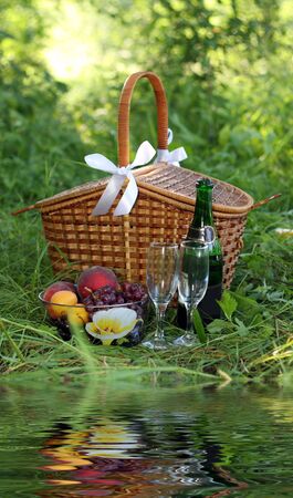 basket for picnic with champagne, fruits and reflection of itの写真素材