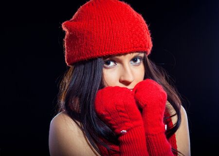 Close-up beautiful face of young woman with red hat and mittenの写真素材