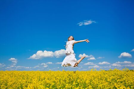 beautiful young woman jumping on field in summerの写真素材