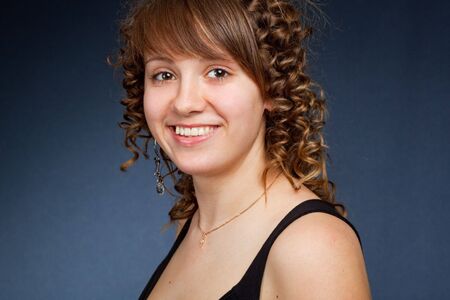 A happy young woman with big smile on dark backgroundの写真素材
