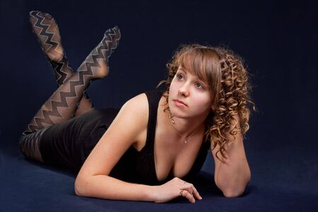 Glamorous young lying woman on black backgroundの写真素材
