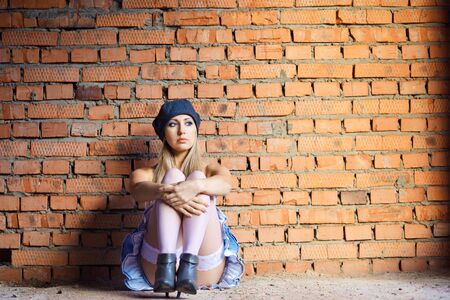 Sexy gorgeous young woman sit near old wallの写真素材